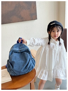 Detail of blue denim kids backpack featuring a washed texture and side pocket on a model