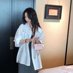 Mini borsa a tracolla rosa con catena dorata indossata da modella in camicia bianca