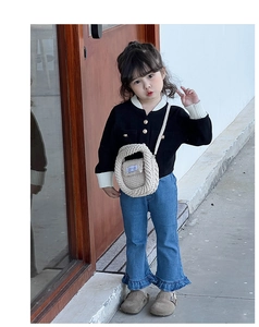 Close-up of a stylish beige crochet crossbody bag paired with a knit cardigan and jeans