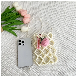 Detail of handmade white pearl beaded crossbody bag with pink crochet peach charm