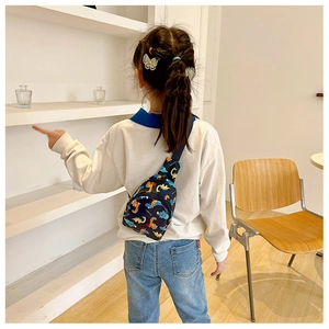 Rear view of a child wearing a dark blue dinosaur chest bag on a minimalist background