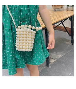 Detail of children's white pearl woven bucket bag with gold accents and drawstring liner