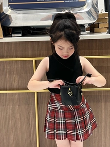 Detail of a black leather girls' bucket bag with gold lock and tag in a cafe setting