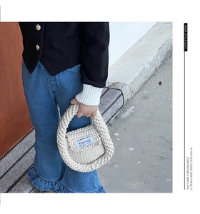 Close-up of cream white cable knit mini handbag showing thick wool texture and flap