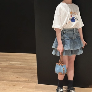 Close-up of a stylish denim bucket bag paired with a blue denim tiered skirt for girls