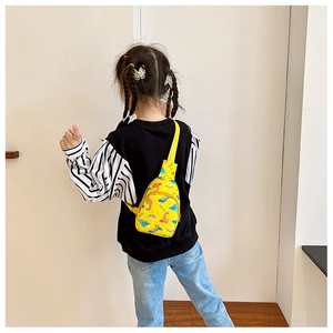 Detail of kids yellow dinosaur chest bag showing the colorful roar prints and straps
