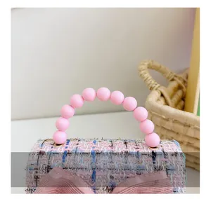 Dettaglio del tweed rosa e del manico di perle lisce su una borsetta da bambina