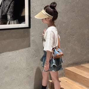 Girl wearing a denim bucket crossbody bag with straw hat and casual summer outfit