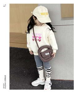 Detail of a brown chunky knit crossbody bag for kids styled with a cream sweatshirt