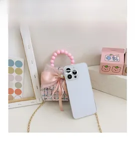 Mini sac en tweed rose avec anse en perles et nœud comparé à un téléphone pour taille