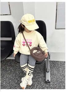 Kids cream sweatshirt with heart and striped leggings styled with a brown knit bag