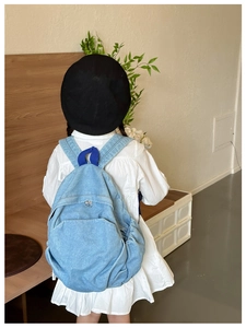 Detail view of denim kids backpack with adjustable straps worn by child model
