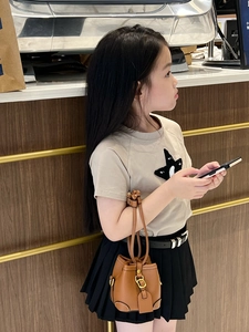 Detail of mini brown leather bucket bag with gold hardware and stylish girl's summer outfit