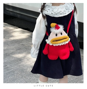 Gros plan d'un sac à bandoulière rouge au crochet fait main porté par une petite fille