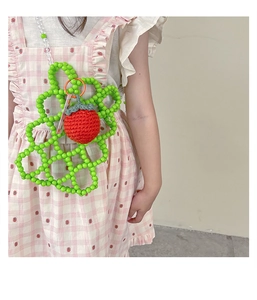 Detail of green beaded flower crossbody bag with a cute strawberry accent for young girls
