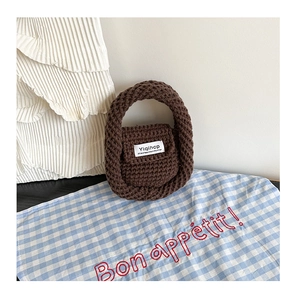 Close-up of handmade dark coffee crochet handbag with chunky wool texture and flap