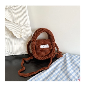Detail of hand-crocheted caramel brown yarn bag with shoulder strap and woven label