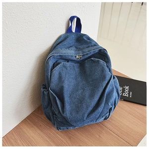 Detail of blue denim kids backpack featuring wash texture, front pocket, and metal zippers