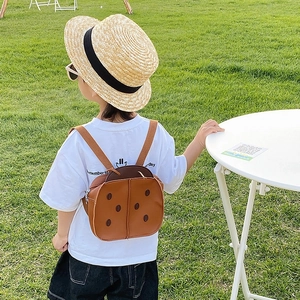 Cute brown ladybug toddler backpack with black dots shown on model in park setting