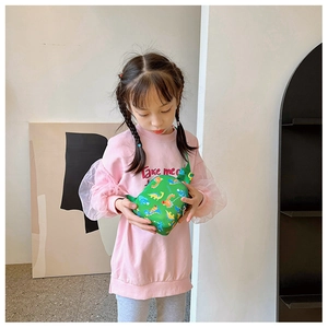 Detailed view of the green dinosaur pattern crossbody chest bag worn by a young child