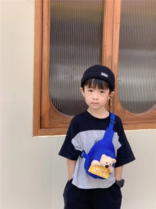 Close-up of blue children's chest bag with plush bear and yellow SMILE tag on boy model