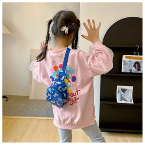 Detail of blue canvas kids chest bag with colorful dinosaur prints and adjustable strap