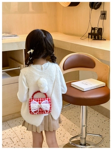 Bambina che indossa una borsa a tracolla in tweed a quadri rossi e bianchi con fiocco