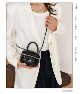 Detail of black quilted mini bag with gold chain strap and decorative buckle