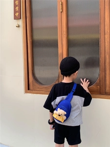 Detail of blue nylon kid's chest bag with plush bear and adjustable strap worn by child