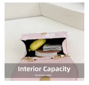 Capacité interne du sac rose à nœud montrant le rangement pour écouteurs et petit miroir