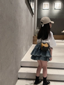 Detail shot of a yellow and black mini bucket bag paired with a blue denim tiered skirt