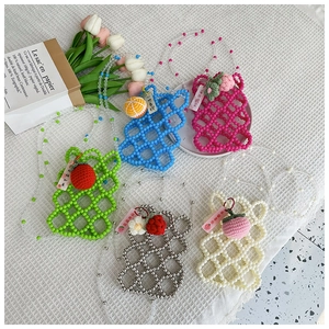 Detail of colorful handmade beaded mini bags with crochet fruit charms and bead straps