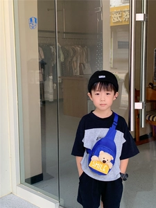 Blue kids chest bag with plush bear and smile label worn by a child in street style