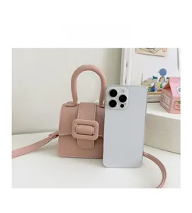 Pink lychee grain mini saddle bag compared with a smartphone for size reference