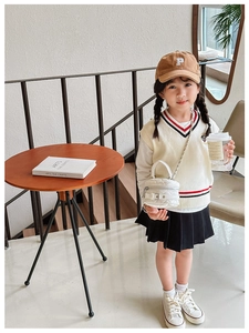 Chic quilted mini crossbody bag styled with a white varsity vest and pleated skirt set