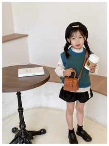 Fashionable girl wearing a vintage brown mini saddle bag with a knit vest and skirt