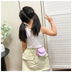 Detail of mini light purple crossbody bag with crocodile texture on a child