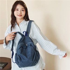 Simple lightweight denim backpack for kids with blue top handle shown on a model