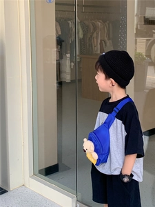 Close-up of child wearing a bright blue chest bag with a cute plush bear decoration