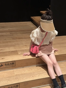 Little girl in pink bucket bag and lace shirt outfit sitting on wooden stairs