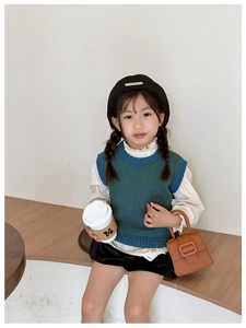 Detail of kids knit vest with blue and green argyle pattern and ribbed hem edges