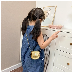 Detail of a mini gold crossbody bag for kids with crocodile texture and white button