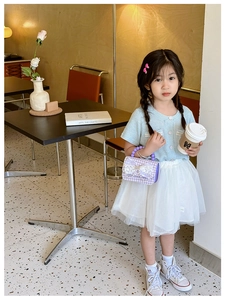 Dettaglio di borsa per bambina a quadri viola con manico di perle e fiocco in pizzo