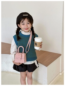 Pink lychee texture mini saddle bag shown on a child model in a cozy indoor setting