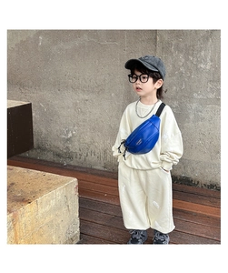 Détail du sac banane enfant bleu royal avec logo sport sur sweat blanc cassé tendance