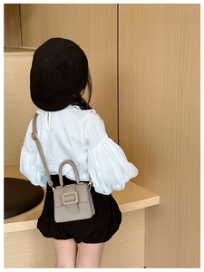 Detailed back view of a taupe litchi pattern mini saddle bag for girls worn by child