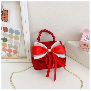 Détail du sac fille en tweed rouge avec grand nœud en satin et anse en perles rouges
