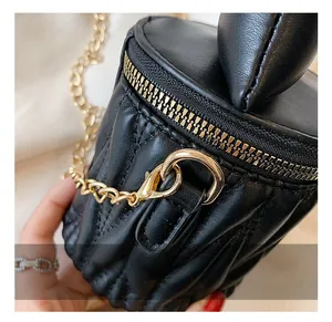 Gros plan détaillé sur les ferrures dorées et le cuir noir matelassé d'un mini sac bandoulière