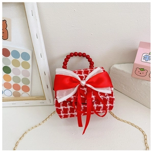 Détail d'un sac à main écossais rouge et blanc avec nœud satiné et poignée perle