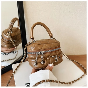 Close-up of brown quilted mini handbag featuring a metal chain strap and buckle detail
